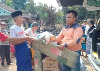 BANTUAN: Relawan BPBD Kecamatan Cirinten, Toni saat menyerahkan bantuan logistik kepada Arsiman korban kebakaran di Kampung Cihaladan, Desa Badur, Kecamatan Cirinten, Minggu (23/8). (MULYANA/SATELIT NEWS)