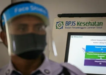 PAKAI PELINDUNG WAJAH : Petugas keamanan BPJS Kesehatan menggunakan pelindung wajah dan masker sesuai protokol Covid-19 di Kantor BPJS Kesehatan, Cikokol, Kota Tangerang, Rabu (1/7). (DEDE KURNIAWAN / SATELIT NEWS)