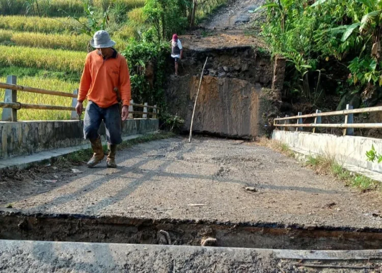 MELINTASI JEMBATAN PUTUS: Seorang warga saat melintasi jembatan putus akibat di terjang banjir di Desa Hariang, Kecamatan So bang. Putusnya jembatan tersebut akibat meluapnya sungai Cimodene Girang, pasca diguyur hujan deras. (DOK BPBD LEBAK)