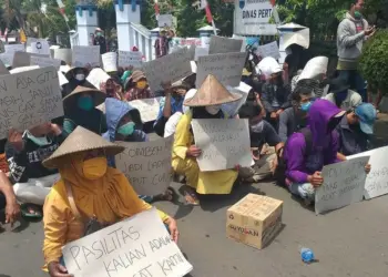 BENTANGKAN KECAMAN: Ratusan petani Sindangresmi duduk di jalanan depan kantor Distan Pandeglang, sambil membentangkan kencaman dan berorasi pada saat melakukan unjuk rasa, Selasa (8/9). (NIPAL/SATELIT NEWS)