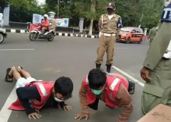 BERIKAN SANKSI: Petugas Gabungan Penegakan Perbup 55 Tahun 2020, sedang memberikan sanksi kepada warga yang melanggar protokol kesehatan, saat menggelar razia di Alun-alun dan Pasar Pandeglang, Minggu (13/9). (NIPAL/SATELIT NEWS)