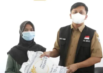 SERAHKAN BANTUAN BERAS–Wabup Pandeglang, Tanto Warsono Arban, secara simbolis menyerahkan bantuan beras kepada seorang KPM, di Aula Kantor Kecamatan Sindangresmi, Senin (26/7/2021). (ISTIMEWA)