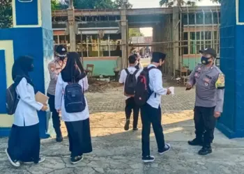 PENGAWASAN PROKES–Para personel Polsek Pandeglang Kota, sedang melakukan pengecekan suhu tubuh para siswa yang hendak mengikuti PTM, dan memberikan masker, di SMPN 1 Pandeglang, Jumat (10/9/2021). (NIPAL SUTIANA/SATELITNEWS.ID)