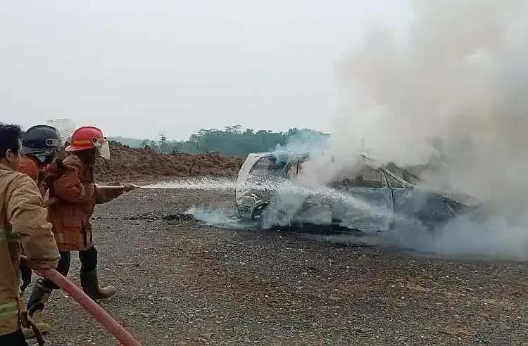 Petugas Damkar sedang memadamkan api yang sempat membakar mobil, akibat dipicu sebuah laptop yang meledak. (ISTIMEWA)