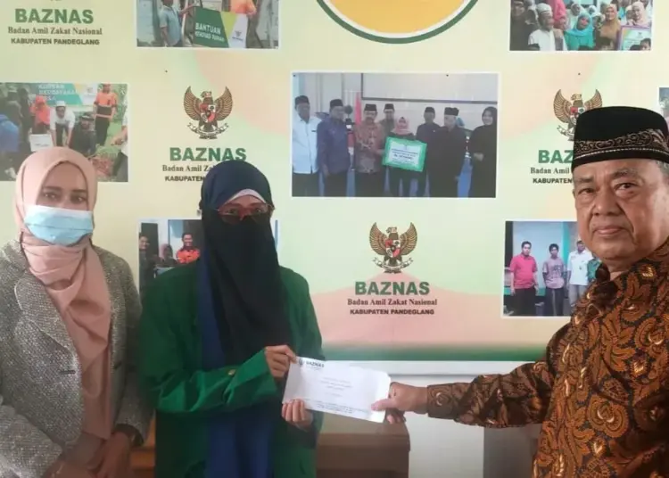 BERIKAN BANTUAN–Wakil Ketua Baznas Pandeglang, H.M. Acang, secara simbolis menyerahkan bantuan beasiswa kepada seorang mahasiswa, di kantor Baznas Pandeglang, Selasa (12/10/2021). (ISTIMEWA)