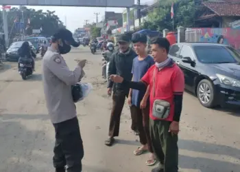 BAGIKAN MASKER–Personel Polsek Labuan, sedang membagikan masker kepada pengguna Jalan, di Jalan Raya Labuan-Carita, tepatnya di wilayah Pasar Labuan, Minggu (24/10/2021). (ISTIMEWA)