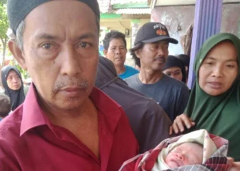 Seorang warga menggendong bayi yang ditemukan di sawah, Selasa (11/1/2022). (ISTIMEWA)