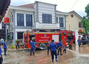 Petugas BPBD Kabupaten Serang, membersihkan halaman kantor BPKAD Kabupaten Serang, usai terendam banjir, Selasa (1/3/2022). (ISTIMEWA)