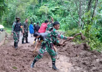 Anggota Koramil 0102/Cadasari, bergotong – royong bersama warga, membersihkan longsoran tanah di jalan yang menghubungkan Desa Kaduengang dan Pasir Peuteuy, Kecamatan Cadasari, Kabupaten Pandeglang, Selasa (1/3/2022). (ISTIMEWA)