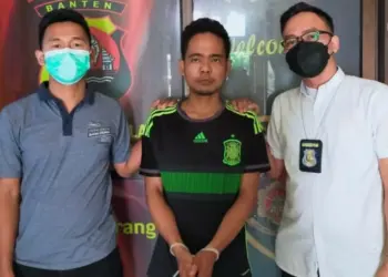 Didampingi dua anggota Polsek Pandeglang Kota, tangan pelaku (tengah) terlihat diborgol, Selasa (22/3/2022). (ISTIMEWA)