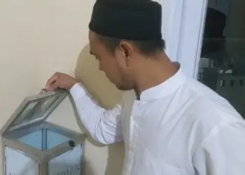 DIBOBOL–Ketua DKM Musala Al-Muqodas, Ustaz Maman sedang menujukan kondisi kotak amal usai dibobol maling, Senin (18/4/2022). (NIPAL SUTIANA/SATELITNEWS.ID)