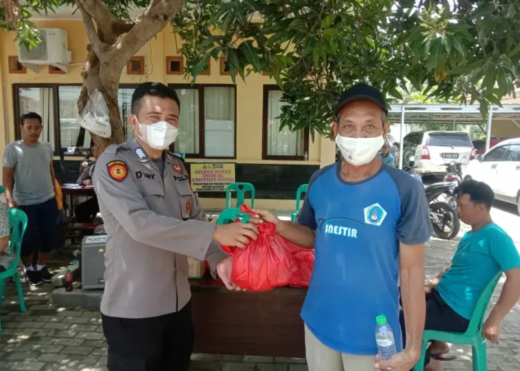 Seorang Personel Kepolisian dari Polres Serang, bagikan sembako kepada warga kurang mampu, Minggu (3/4/2022). (ISTIMEWA)