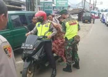 Personel Polri dan TNI, sedang menaikan nenek-nenek ke motor untuk diantarkan ke RSUD Berkah Pandeglang, saat terjebak macet di Jalan Raya Mengger-Caringin, Selasa (3/5/2022).  (ISTIMEWA)