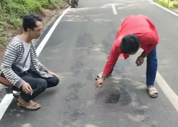 Aktivis GMNI Pandeglang, sedang memilok jalan Kondangjaya-Pasirkoer di Kecamatan Cisata, yang baru selesai dibangun tapi sudah bolong, Senin (6/6/2022). (ISTIMEWA)