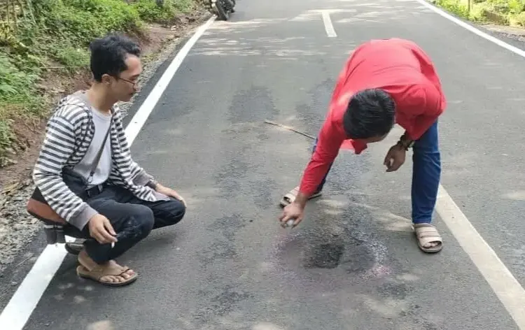 Aktivis GMNI Pandeglang, sedang memilok jalan Kondangjaya-Pasirkoer di Kecamatan Cisata, yang baru selesai dibangun tapi sudah bolong, Senin (6/6/2022). (ISTIMEWA)