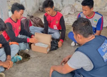 Giwan, didampingi teman-temannya sedang membuka dus untuk melihat sepasang sepatu, yang diberikan relawan Laznas Rumah Yatim, Senin (18/7/2022). (ISTIMEWA)