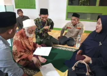 Abuya KH. Muhtadi Dimyati Cidahu, sedang membubuhkan tanda tangannya di secarik kertas, sebagai bukti merestui dan mendukung penuh kegiatan HSN 2022 di Pandeglang. (ISTIMEWA)