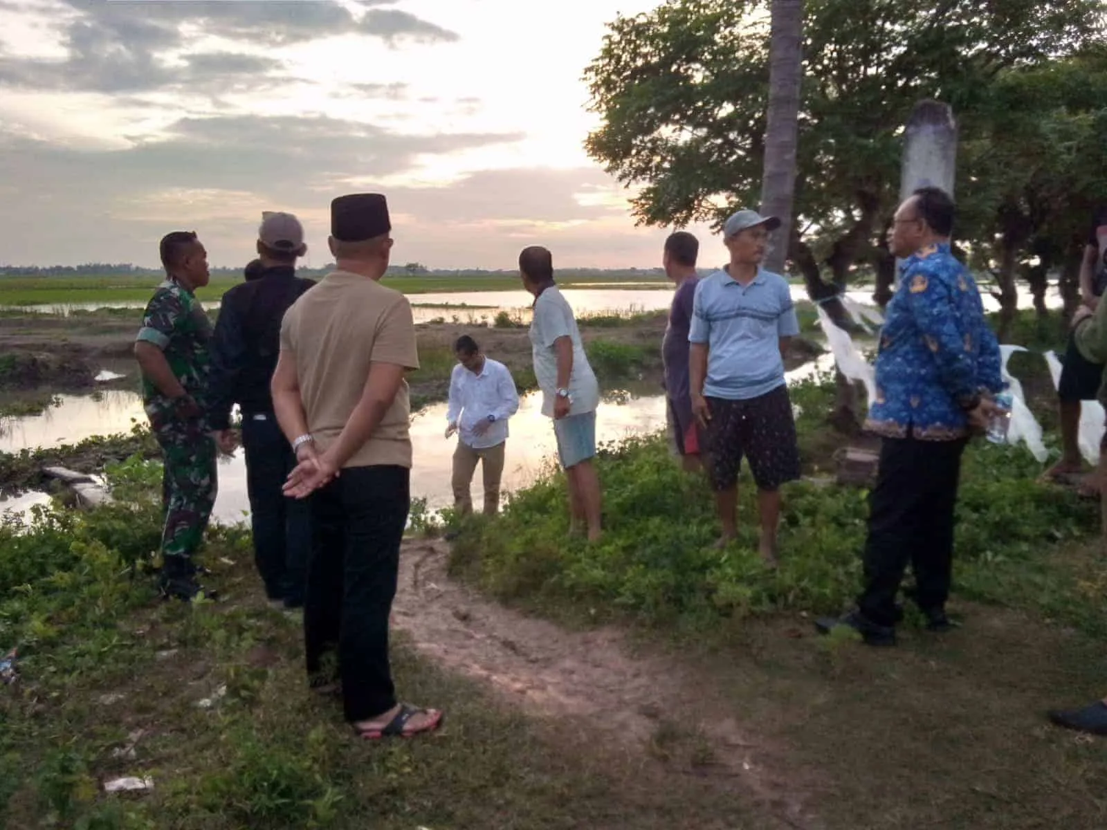 DATANGI LOKASI: Camat Pakuhaji Asmawi (batik biru) bersama Kades dan warga saat menyambangi lokasi anak tenggelam di danau bekas galian di Desa Kalibaru, Kecamatan Pakuhaji, Senin (20/2/2023). (ISTIMEWA)