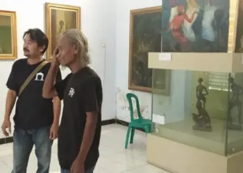 MELIHAT LUKISAN–Gebar Sasmita, sedang menunjukkan karya seni lukisnya saat Pameran Tunggal, di Gedung Bale Budaya, Dinas Pariwisata dan Kebudayaan (Disparbud) Kabupaten Pandeglang. (MARDIANA/SATELITNEWS.COM)