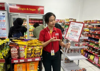 Seorang karyawan minimarket menunjukkan promo di tokonya. (ISTIMEWA)