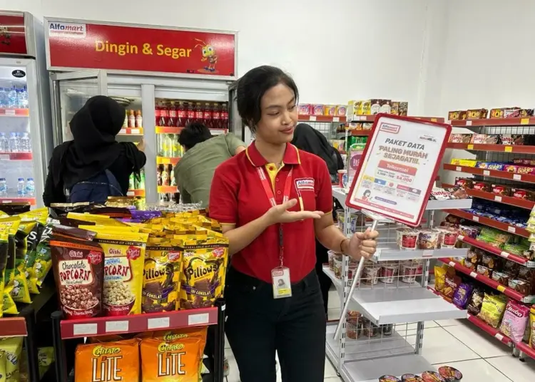 Seorang karyawan minimarket menunjukkan promo di tokonya. (ISTIMEWA)