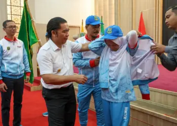 Pj Gubernur Banten Al Muktabar, secara simbolis menyematkan seragam kepada salah satu atlet. (ISTIMEWA)