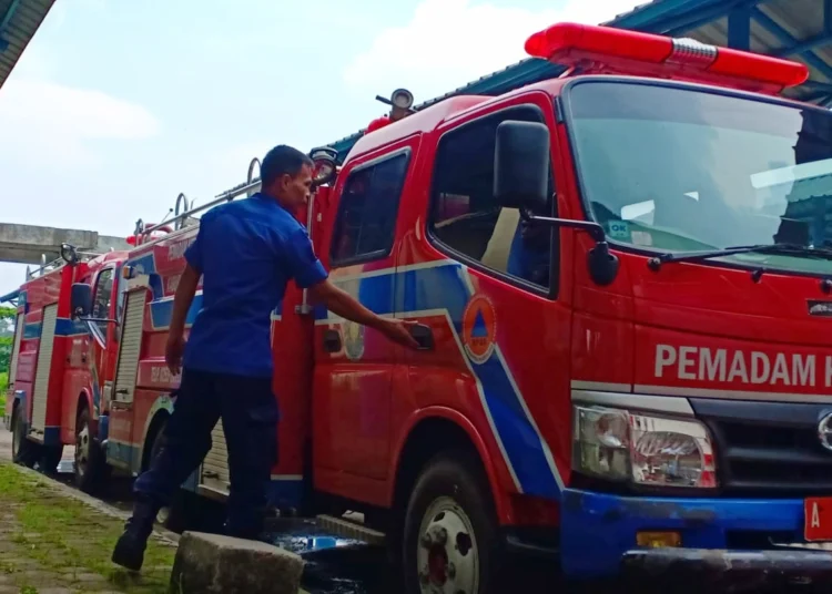 Petugas BPBDPK Kabupaten Pandeglang, memeriksa mobil Damkar yang sedang terparkir, di halaman kantor instansi setempat, Selasa (21/11/2023). (FAHRIE/SATELITNEWS.COM)