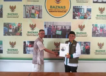 Ketua Baznas Kabupaten Pandeglang, Pery Hasanudin (kanan), secara simbolis menyampaikan bantuan keagamaan kepada penerima manfaat, Senin (11/12/2023). (FAHRIE/SATELITNEWS.COM)