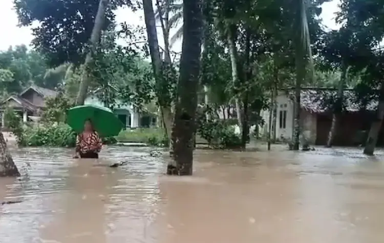 Warga Desa Idaman berjalan di tengah banjir. (iSTIMEWA)