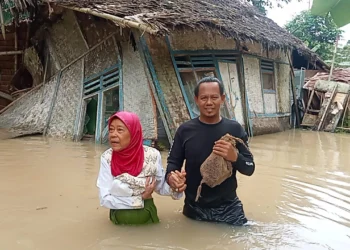 Ketua Perkumpulan Boedak Saung Kabupaten Pandeglang, Ilman, menolong seorang nenek terdampak banjir. (ISTIMEWA)