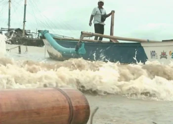 Seorang nelayan memeriksa perahu, di tengah gelombang ombak tinggi di Perairan Selat Sunda. (ISTIMEWA)