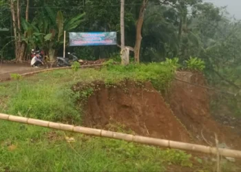 Ruas jalan Cilabanbulan, Kecamatan Menes, Kabupaten Pandeglang, yang longsor, dipasang spanduk protes oleh warga. (ISTIMEWA)