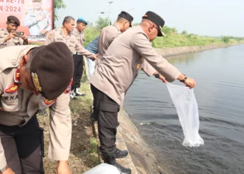 Kapolres Serang, AKBP Condro Sasongko, menebar bibit ikan di Danau Puspemkab Serang, Rabu (26/6/2024). (ISTIMEWA)