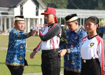 SIMBOLIS: Pj Bupati Andi dan Kepala Badan Kesbangpol Kabupaten Tangerang Rudi Lesmana, secara simbolis menyematkan perlengkapan training center, tanda dibukanya TC Anggota Paskibra Kabupaten Tangerang di sela-sela upacara, Rabu (17/7/2024). (ISTIMEWA)