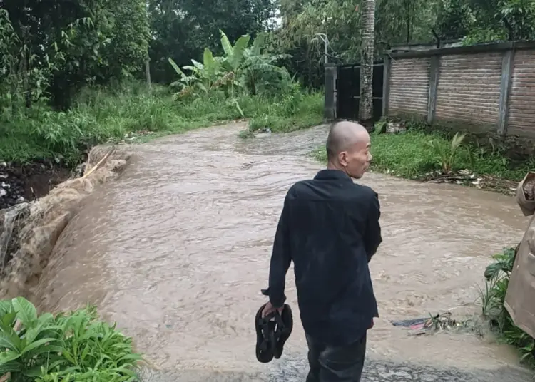 Seorang warga menunjukkan lokasi hanyutnya 3 pelajar, kepada seorang personel Polisi. Hingga kini, korban hanyut masih dalam pencarian. (ISTIMEWA)